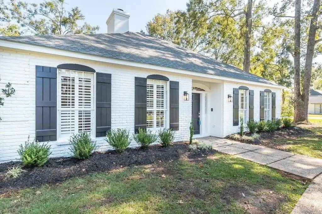 Stunning white painted brick home in Baton Rouge with contrasting black shutters and trim.
