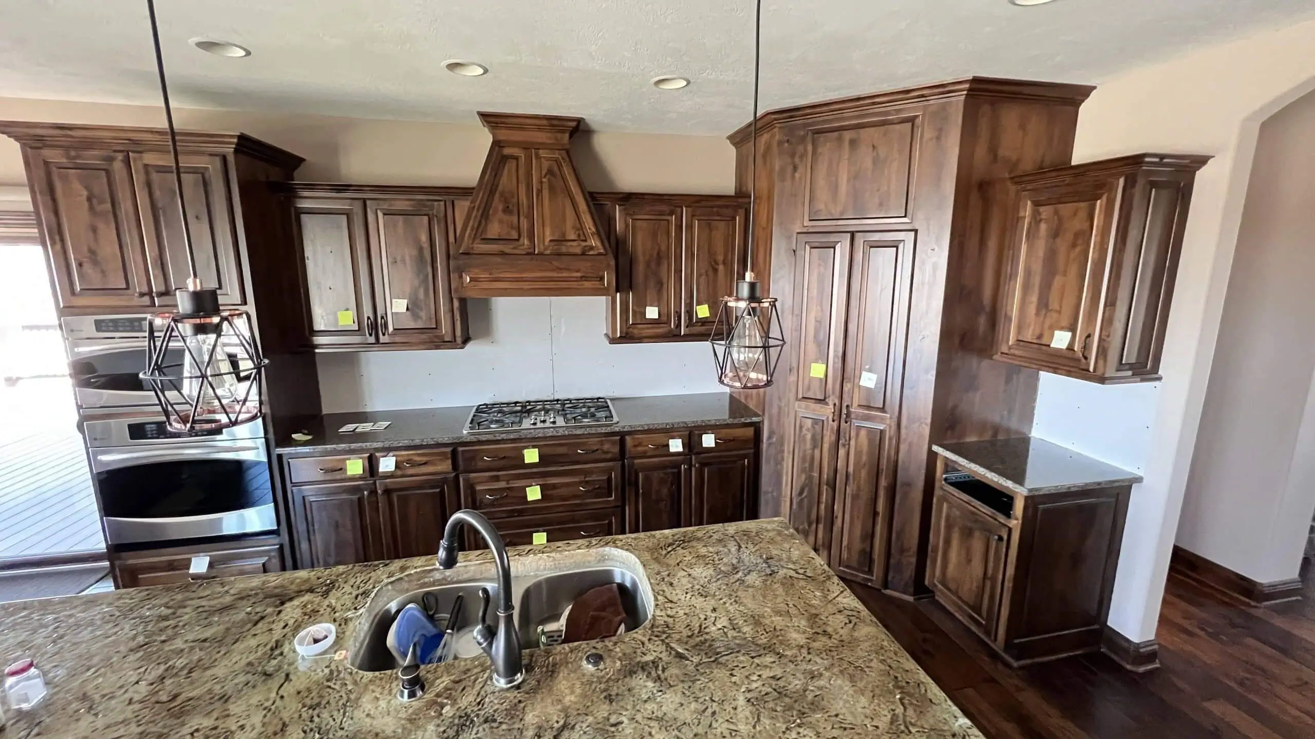 Large kitchen with dark-stained wood cabinets and a matching custom range hood.