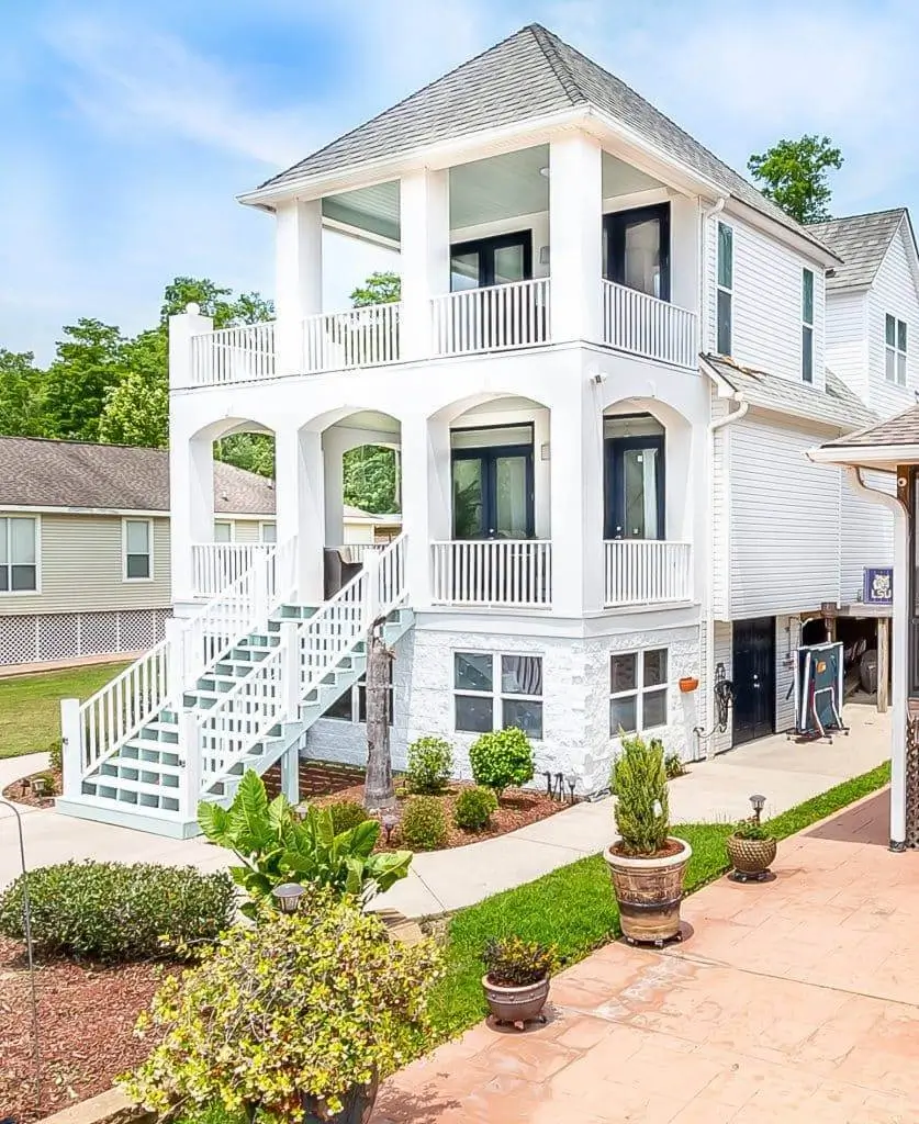Exterior of a multi-story white house with fresh paint, balconies, and custom stairs.