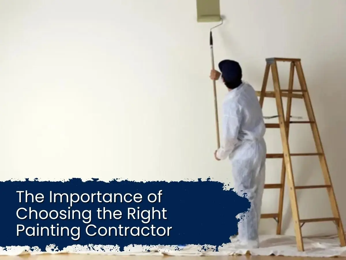 A professional painter in white coveralls using a roller and extension pole to paint a high interior wall.
